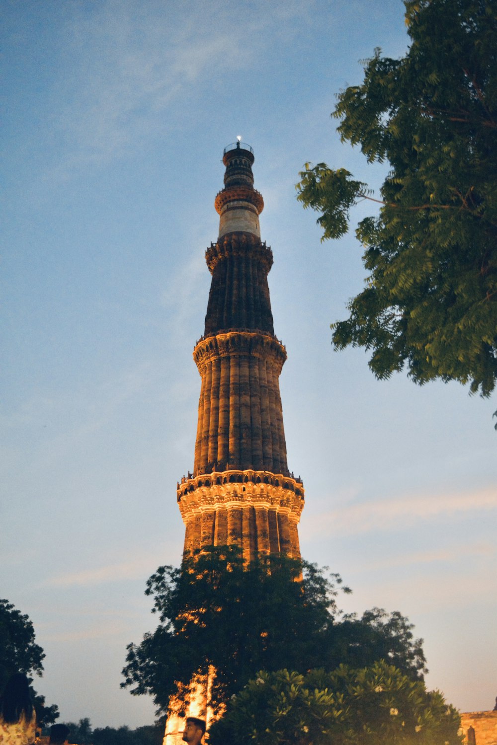 a tall tower with lights at night with Qutub Minar in the background