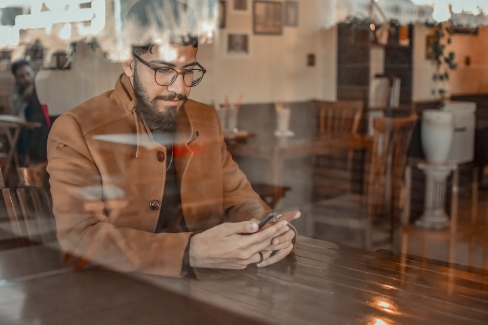 a man sitting at a table looking at his phone