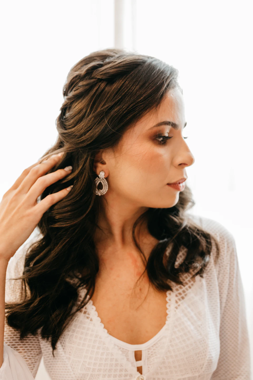Woman's face in close-up view with elegant updo and large silver earrings on white dress