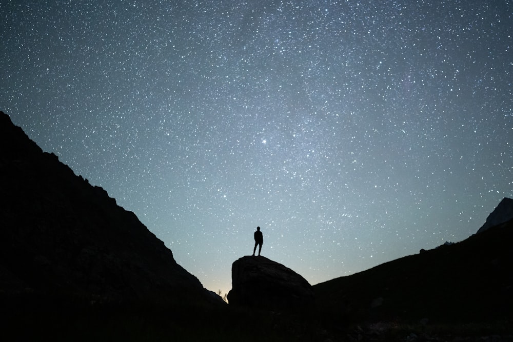 a person standing on a rock looking at the stars in the sky