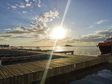 a dock with a boat and the sun in the background