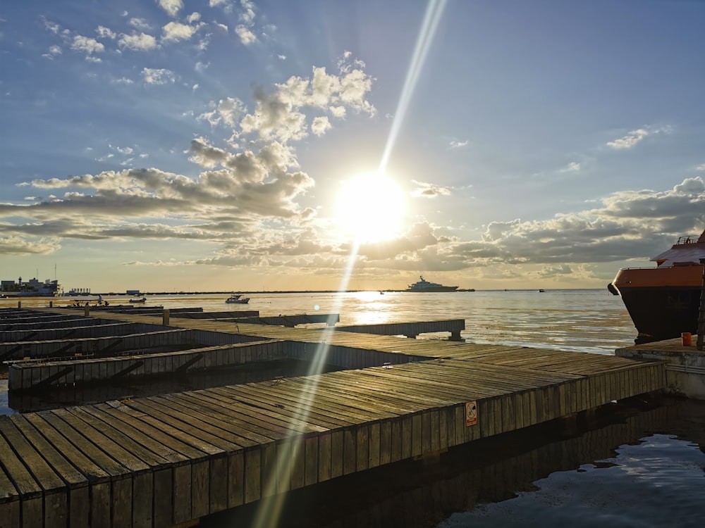 a dock with a boat and the sun in the background