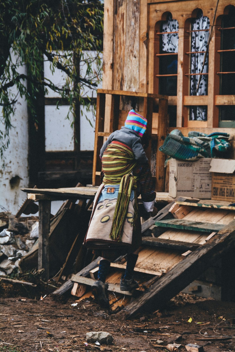 a person in a hat and scarf standing next to a pile of wood