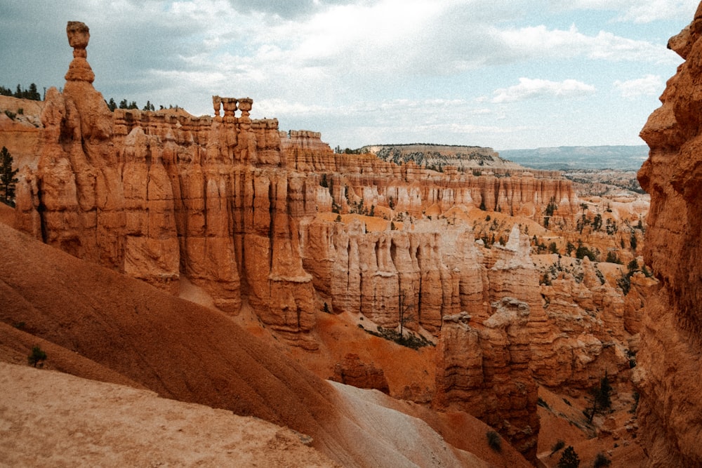 a rocky canyon with a few buildings with Bryce Canyon National Park in the background