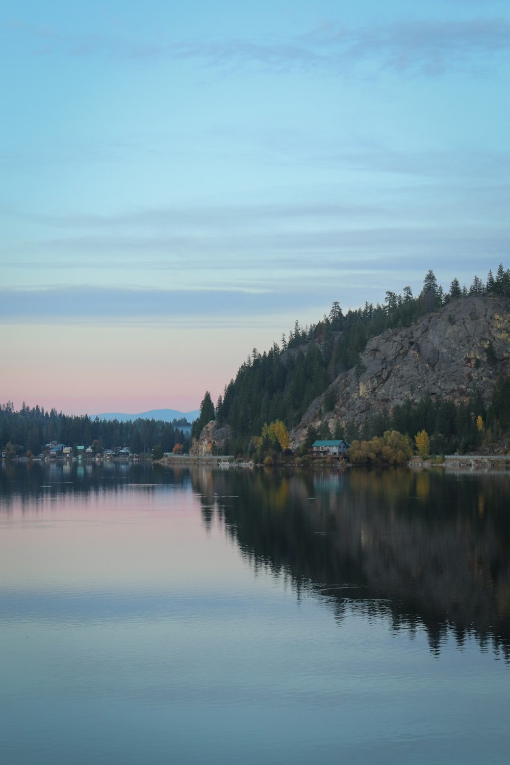 a body of water with a hill and trees on the side