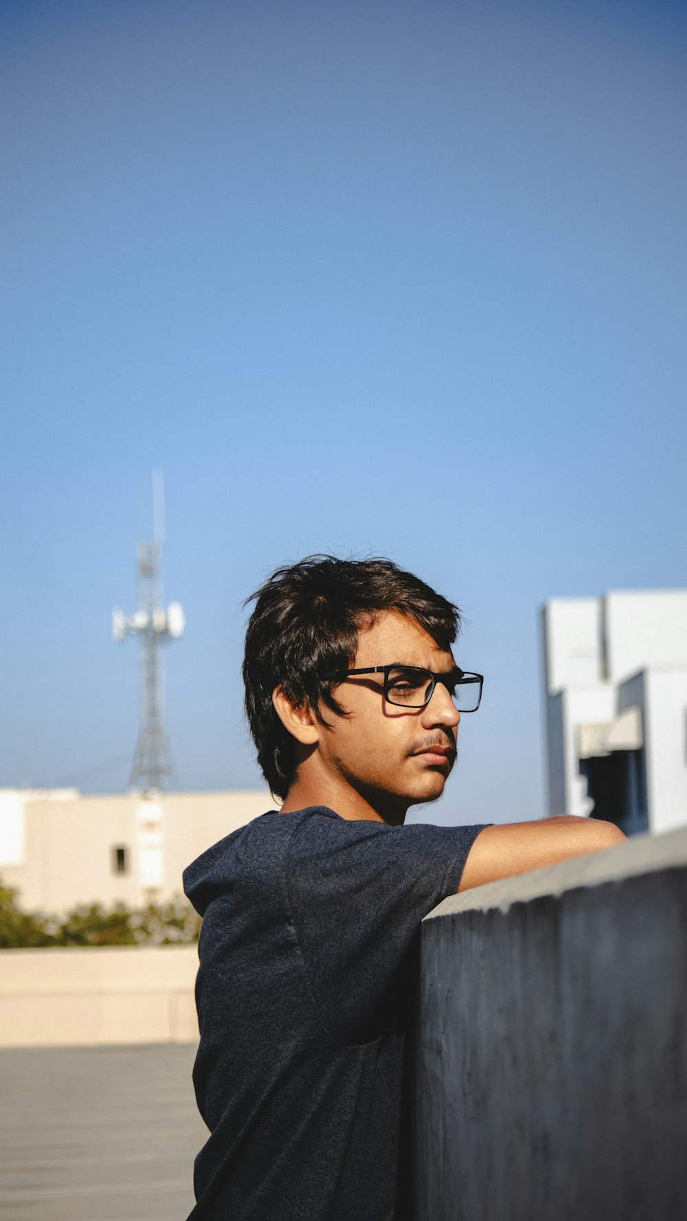 a man with glasses and a blue shirt with a tower in the background