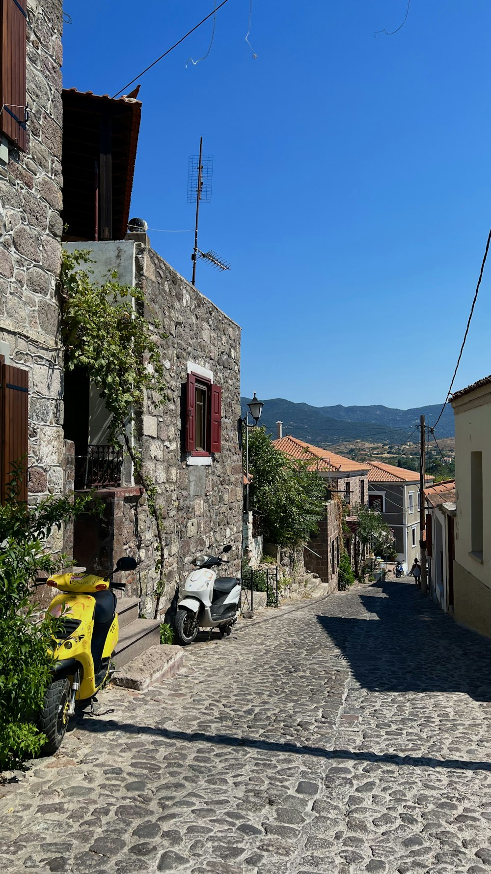 a cobblestone street with buildings and scooters