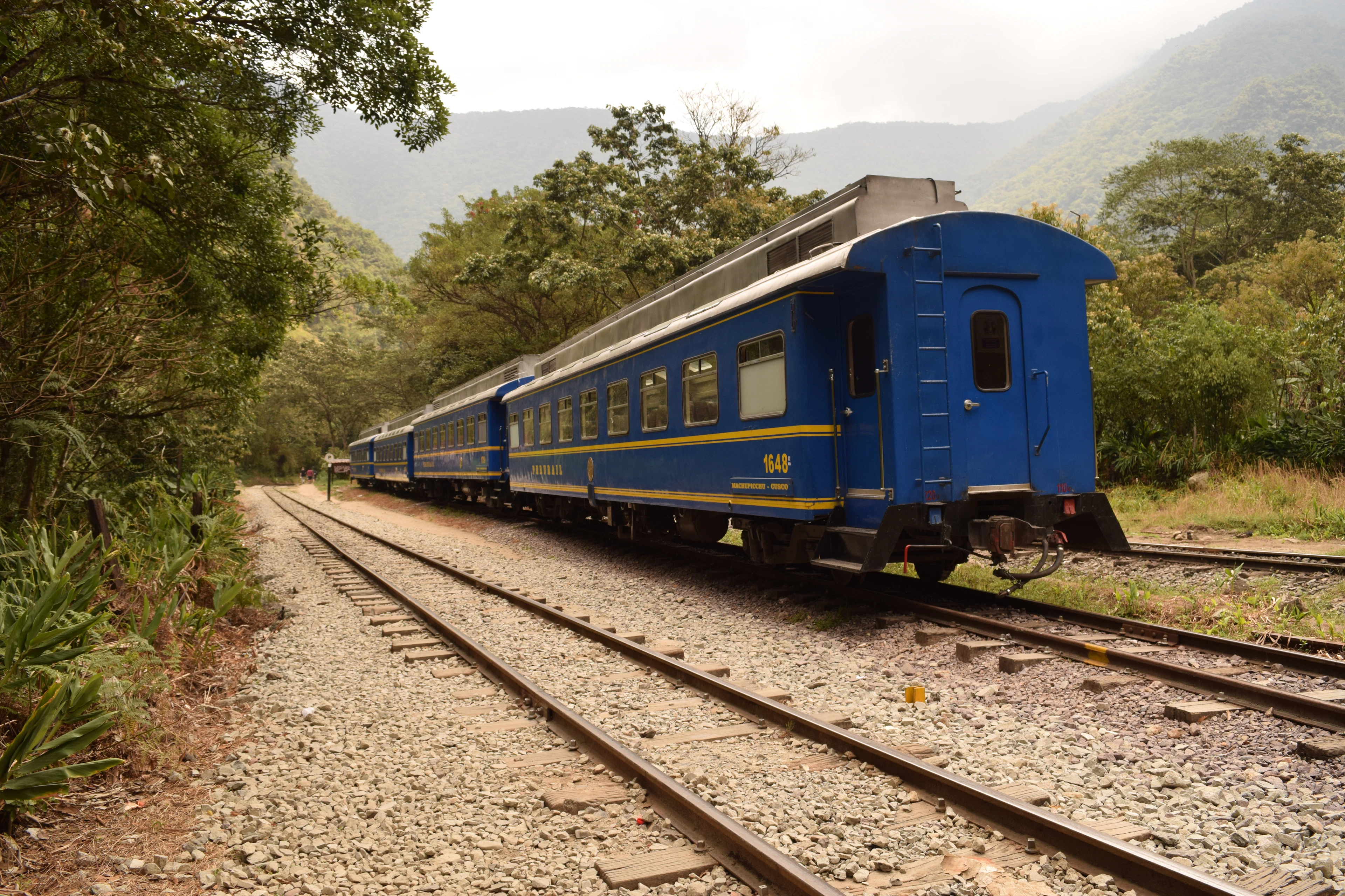 Blue railway carriages among forested mountains at Aguas Calientes, below Machu Picchu