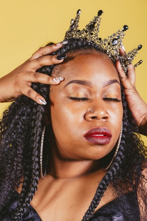 A close-up of hands adjusting a golden crown, symbolizing empowerment.