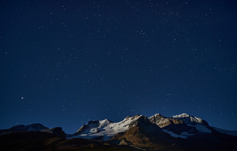 Una montaña nevada con un cielo estrellado arriba