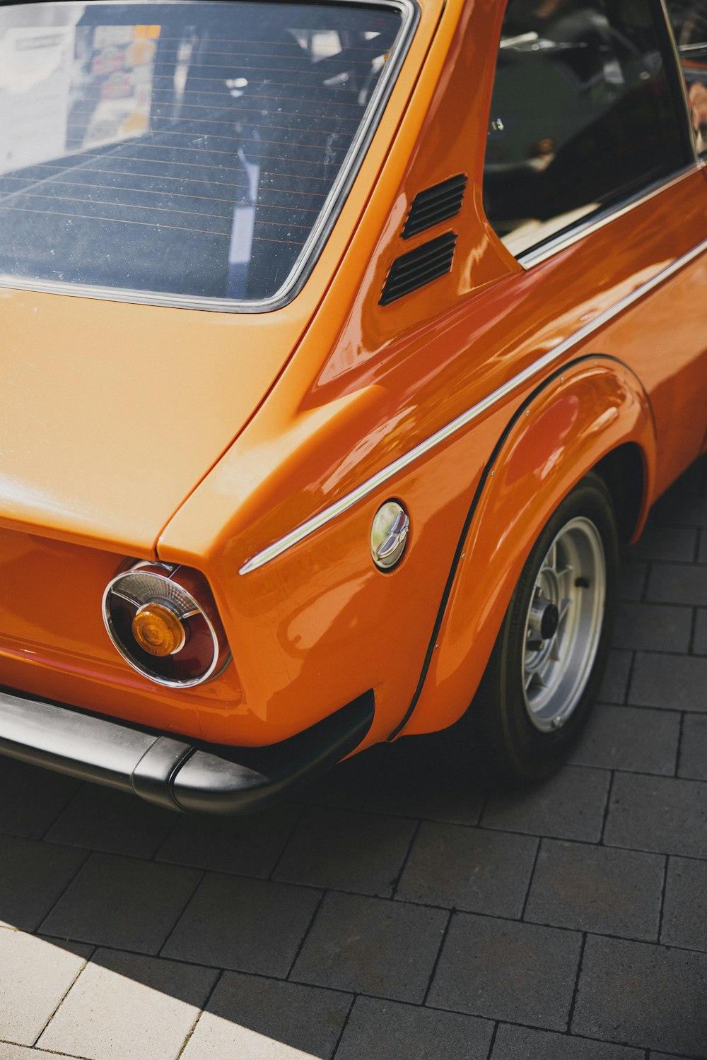 an orange car parked on a brick road