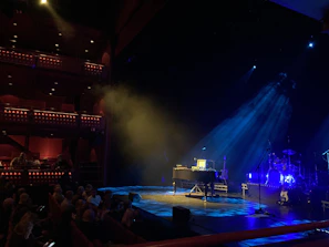 Elegant concert hall stage bathed in deep navy and gold lighting, ready for a flute solo.