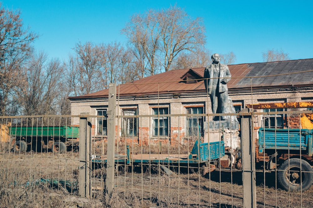 a statue of a person in a suit standing on a fence