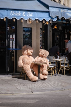 a couple of teddy bears sit on a sidewalk
