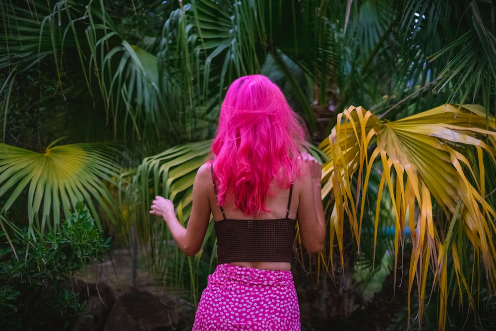 a girl wearing a pink hat and standing in front of a tropical forest