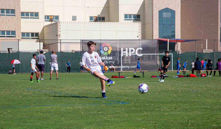 Young players practicing dribbling skills under coach supervision on a sunny field