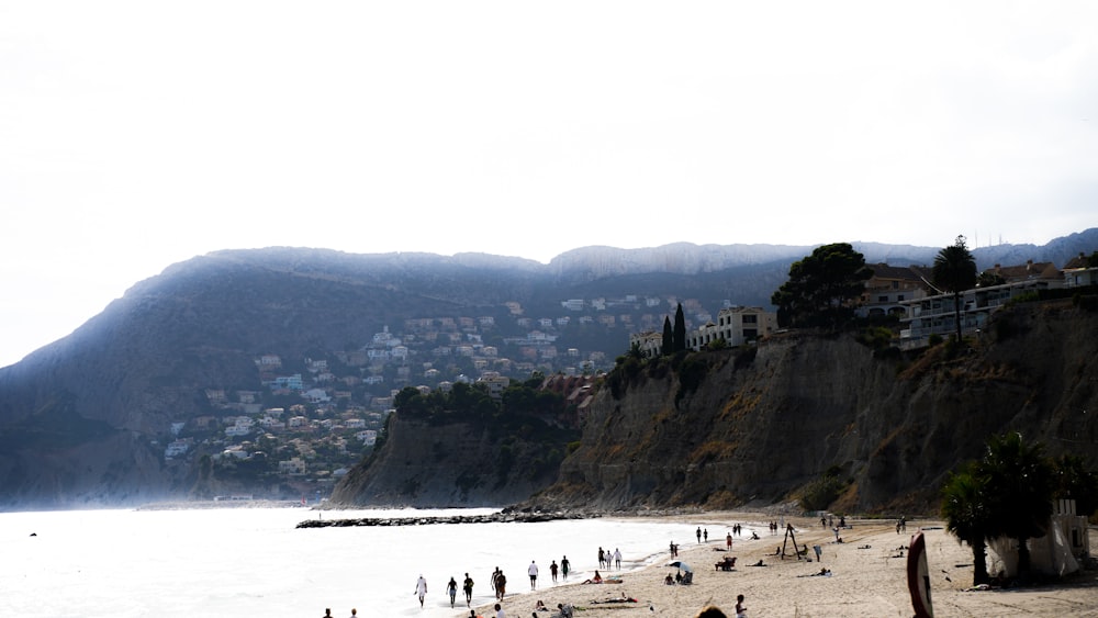 a beach with people and buildings on it by a body of water