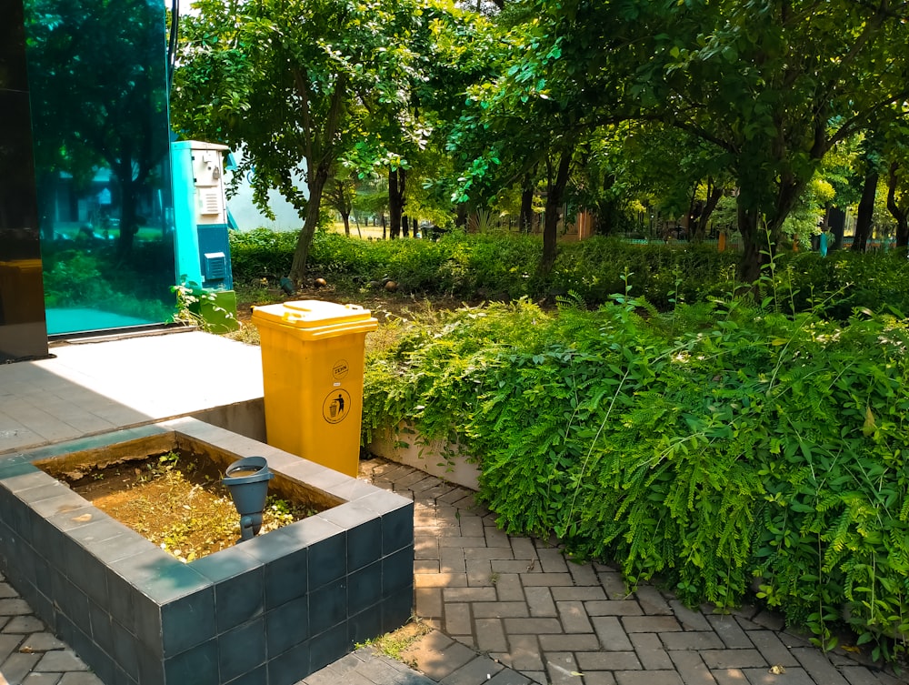 a small garden with a yellow trash can