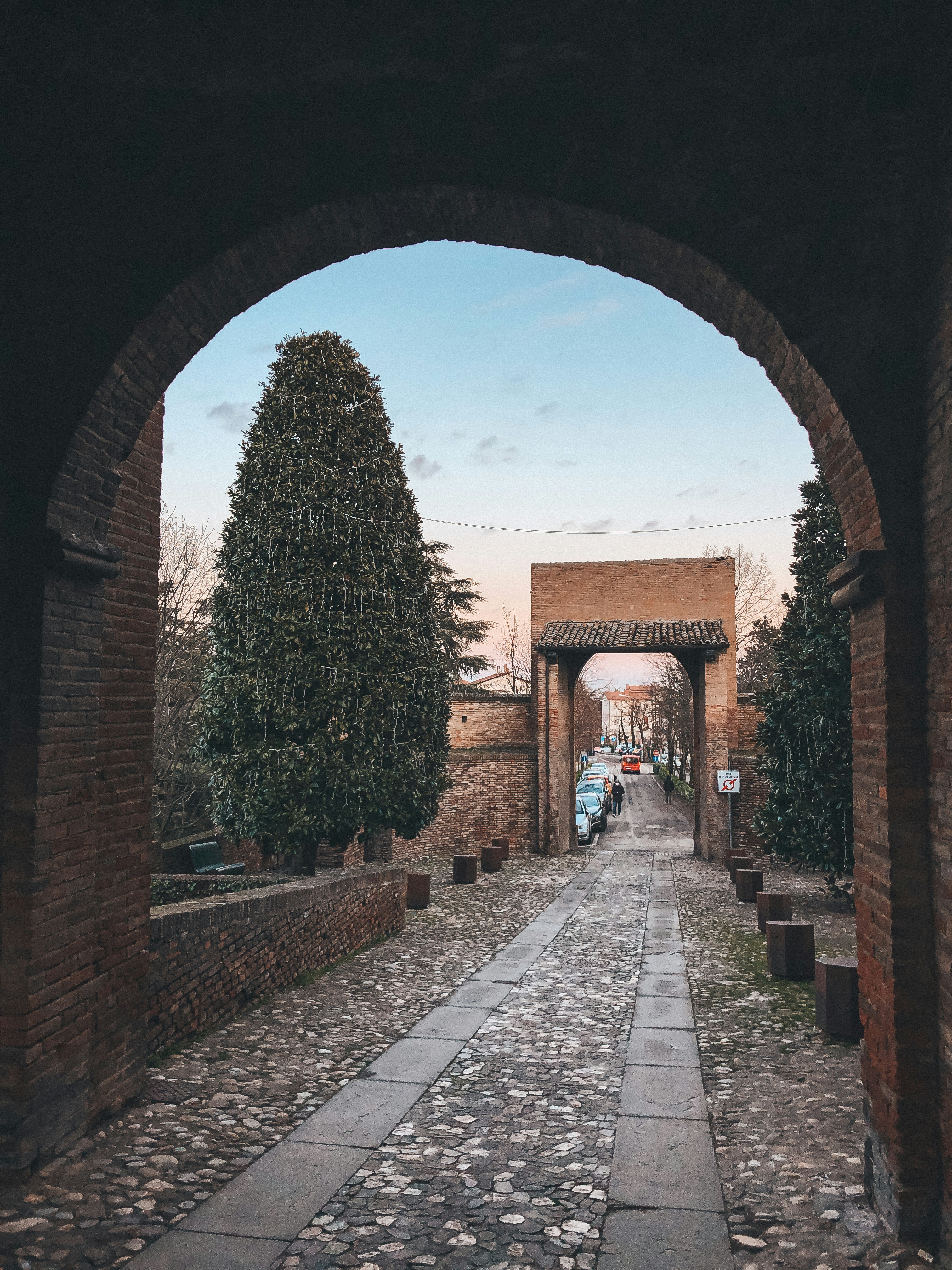 uma passarela de pedra com uma árvore e um edifício ao fundo