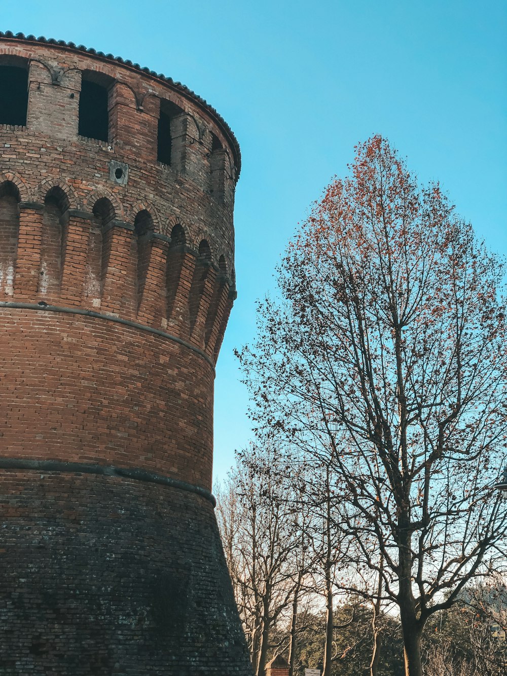 a brick tower with a tree in front of it