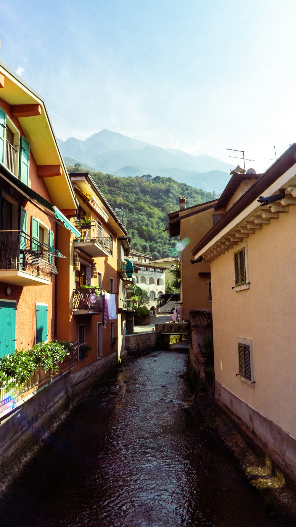 a narrow street with buildings on both sides and a mountain in the background