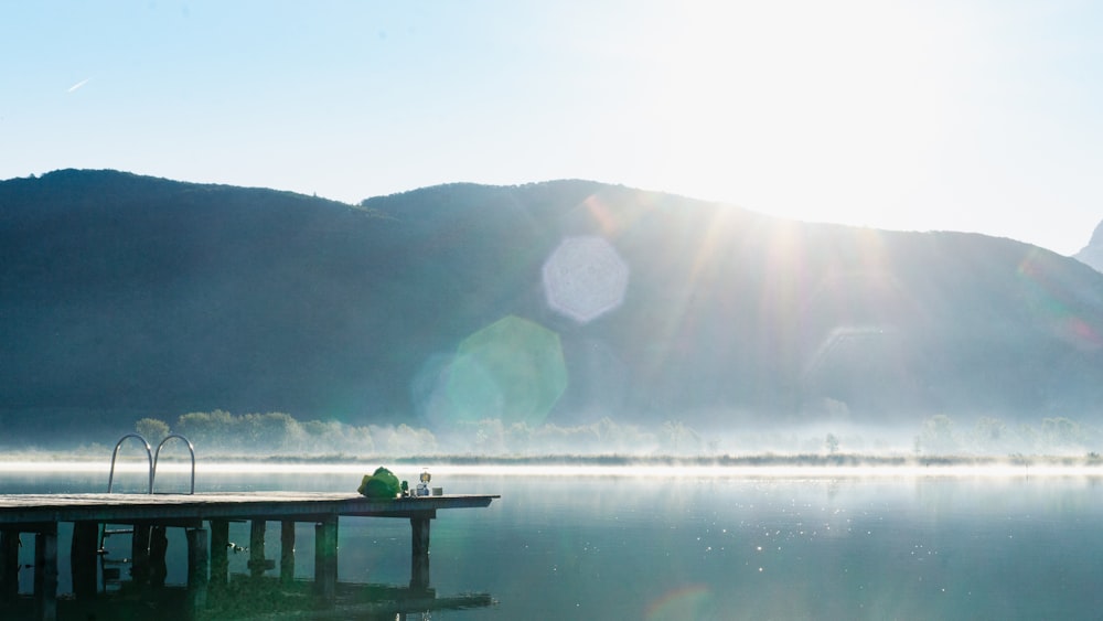 a body of water with a dock and a mountain in the background