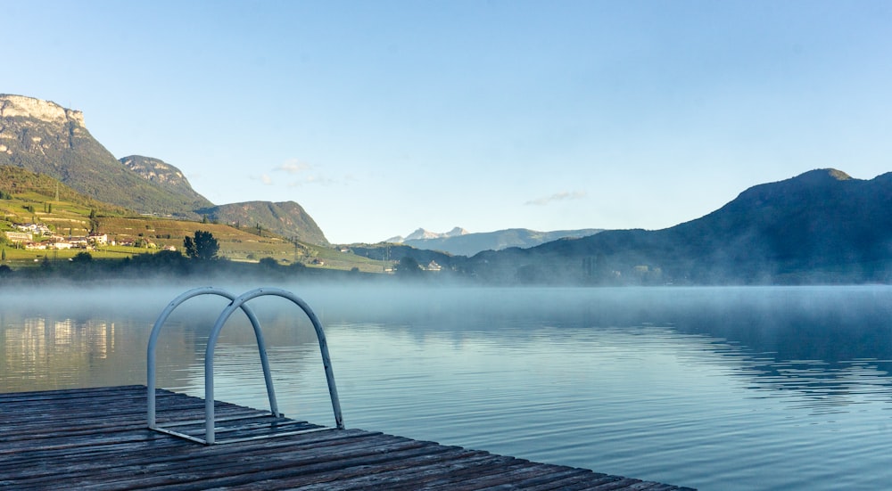 a bench on a dock over a lake with mountains in the background