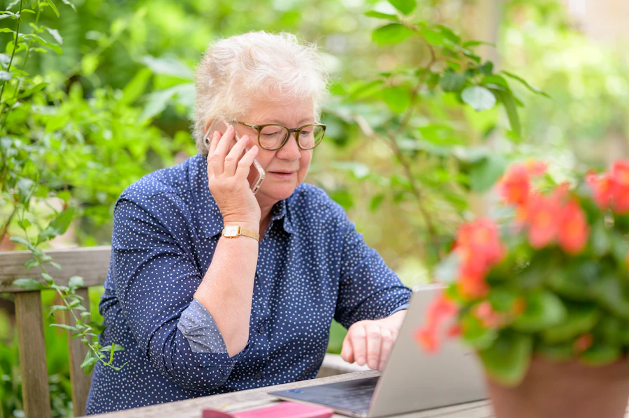 A woman on the phone at home with a laptop open in front of her