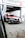 A racing car with a black, red, and white color scheme is positioned in a motorsport garage under a sign that reads 'Century Motorsport BMW M4 GT3'. The car has various brand stickers, including Sonax and Pirelli, and is partially outside the garage ready for a race.