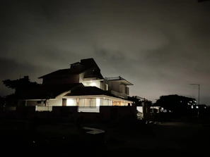 A nighttime shot of a monster house illuminated with warm lighting highlighting its unique architecture
