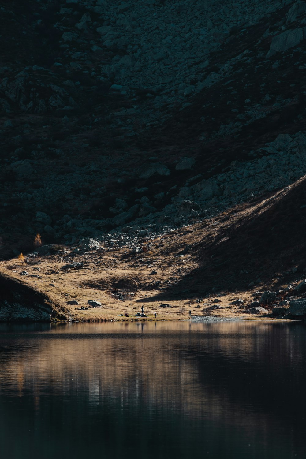 a body of water with a rocky shore and a hill with a hill in the background