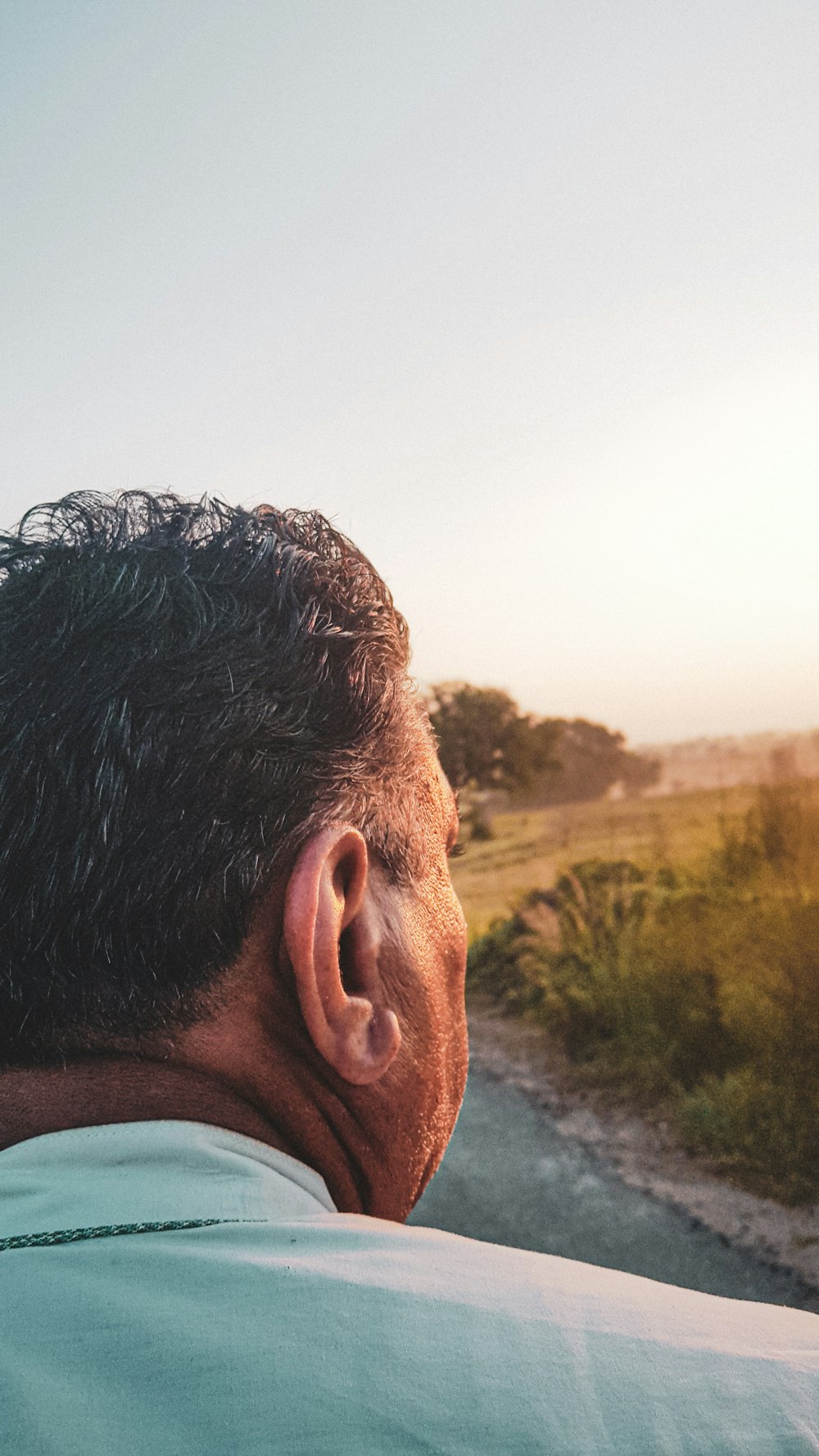 a man's profile with a river and trees in the background