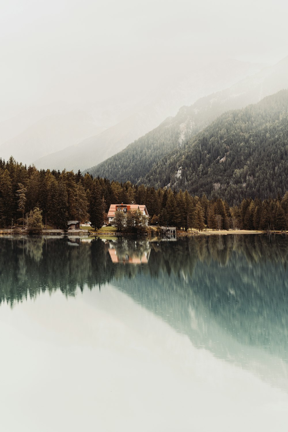 Ein Haus auf einem Hügel an einem See mit Bäumen und einem Berg im Hintergrund