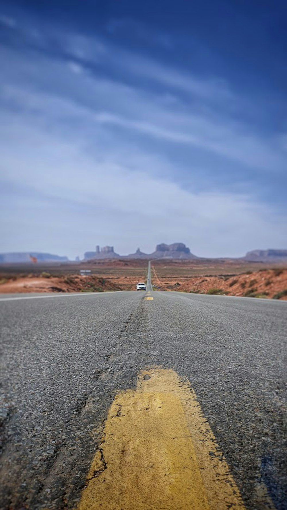 a road with a white car on it and a blue sky above