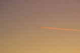 Sunset sky with orange and pink hues highlighting lingering chemtrails.