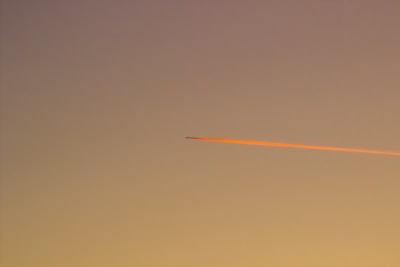 Sunset sky with orange and pink hues highlighting lingering chemtrails.