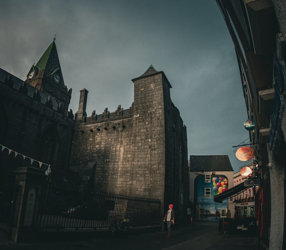 a stone castle with a person walking by it