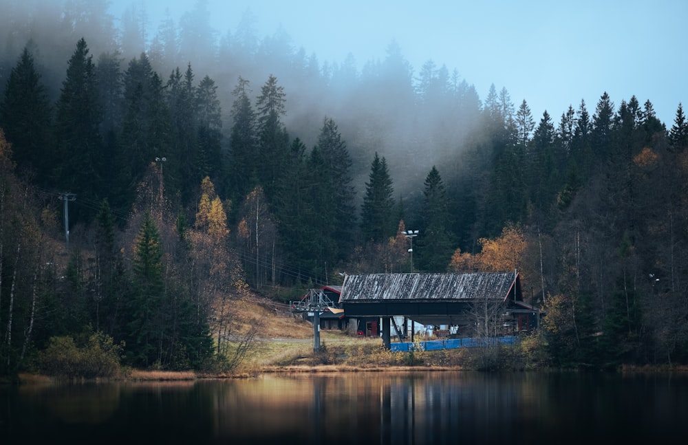 a house on a lake surrounded by trees and fog