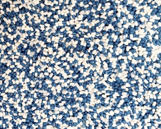 A large number of blue and white capsules scattered randomly, forming a dense, chaotic pattern.