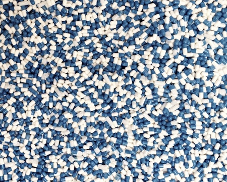 A large number of blue and white capsules scattered randomly, forming a dense, chaotic pattern.