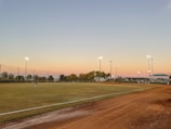 Evening shot of the cage lit up with players taking turns hitting under the lights.