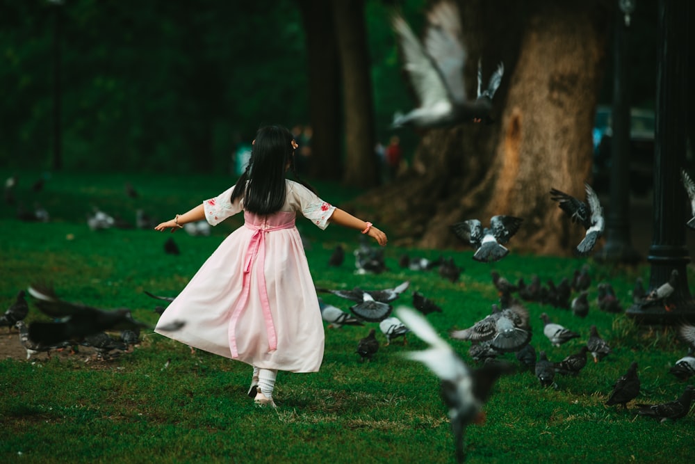 a girl feeding a flock of pigeons
