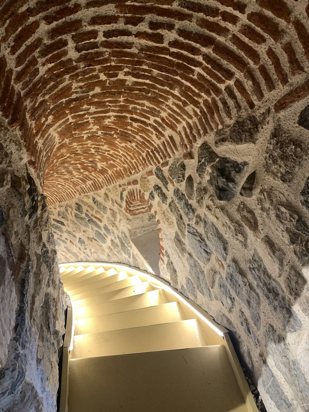 a stone tunnel with a light at the end