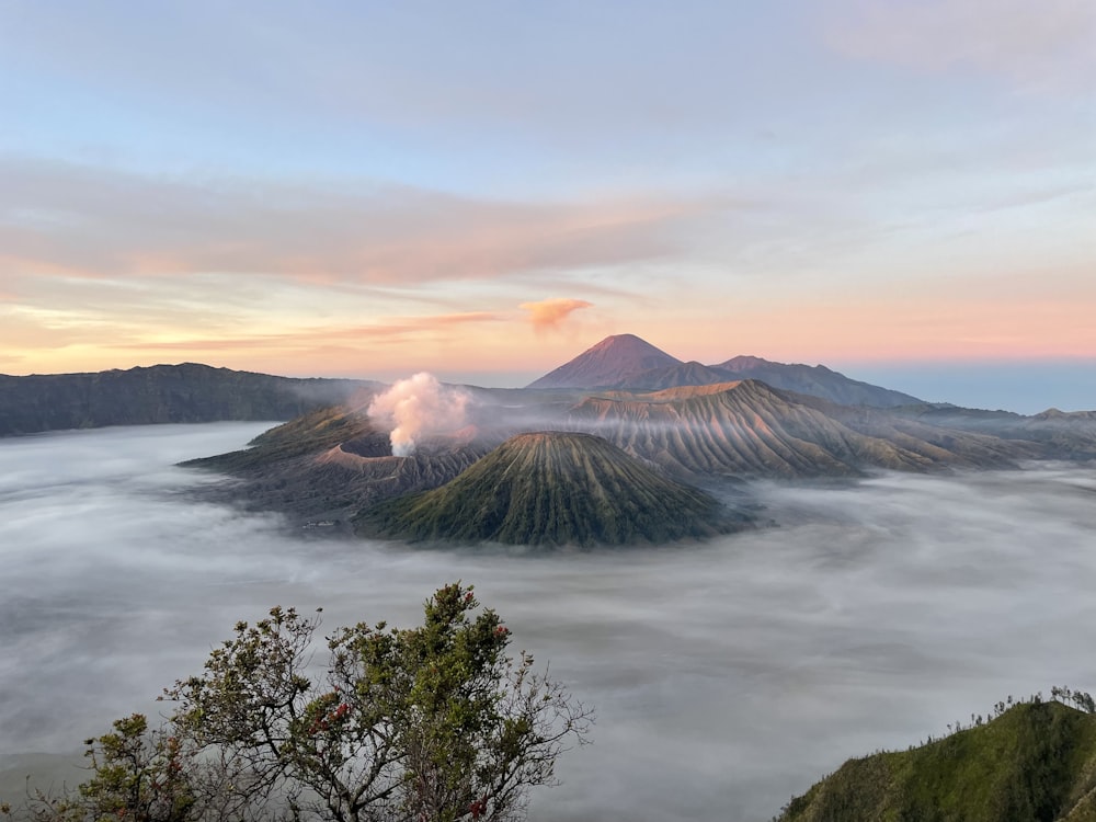 a body of water with trees and mountains in the background with Mount Bromo in the background