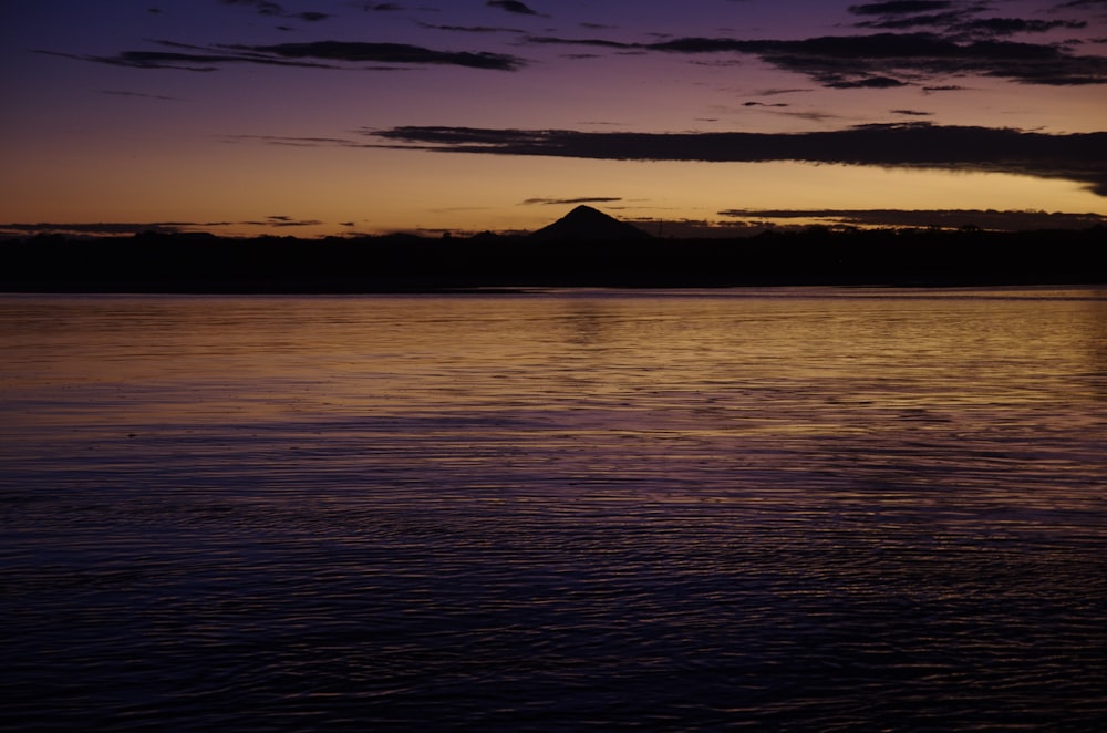 a body of water with a mountain in the distance