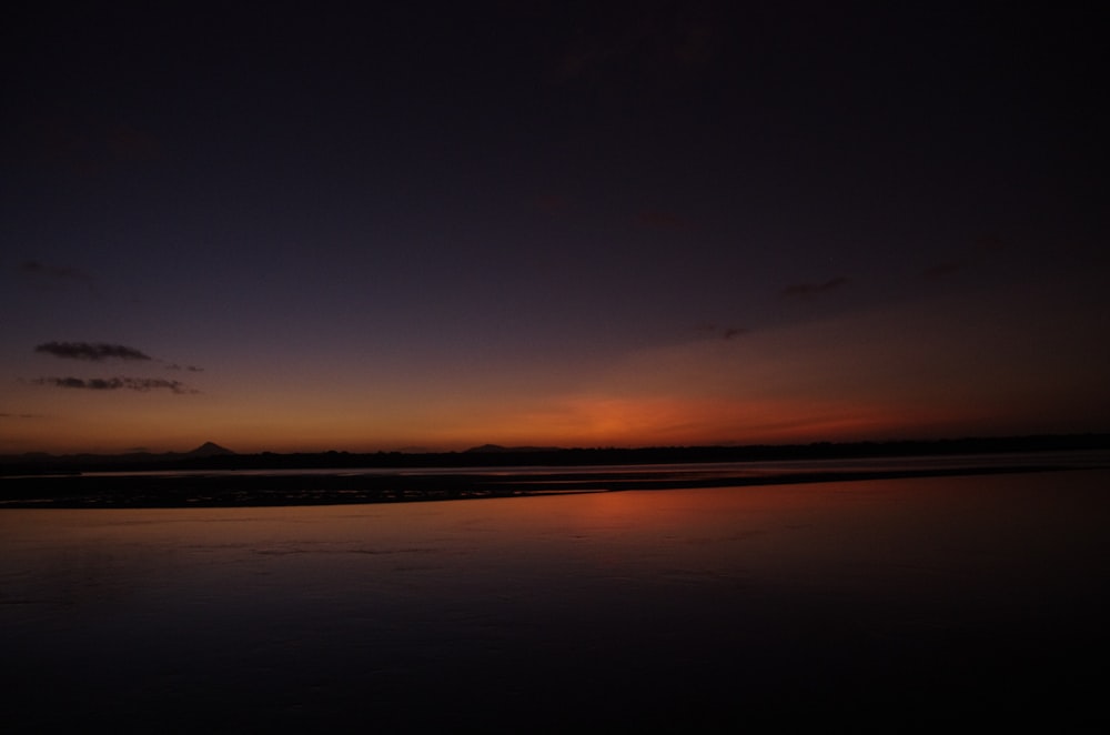 a body of water with a sunset in the background