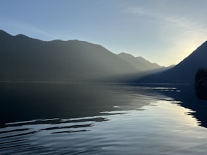 A tranquil lake reflecting the surrounding mountains at sunset