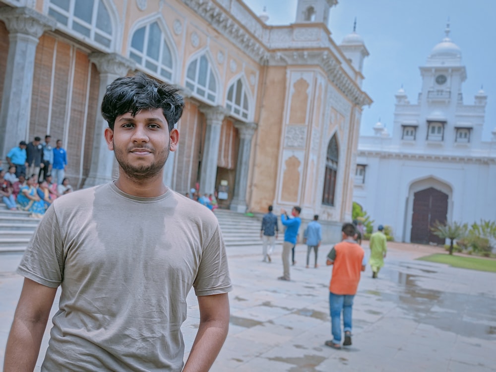 a man standing in front of a building with people walking around