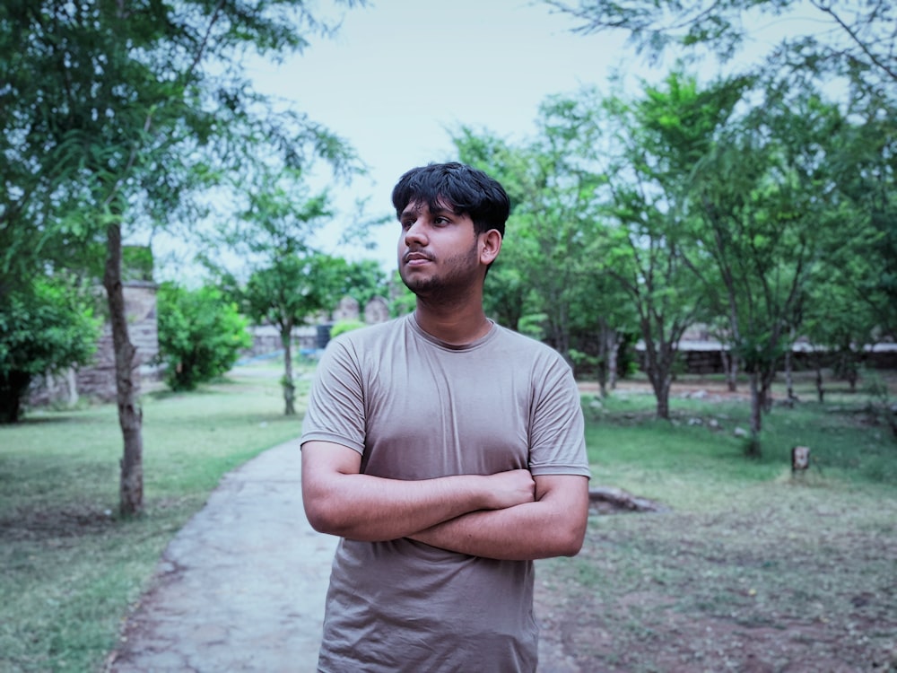 a man standing on a path with trees and grass