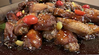 Sweet and tangy mango wing sauce dripping off a perfectly cooked wing.